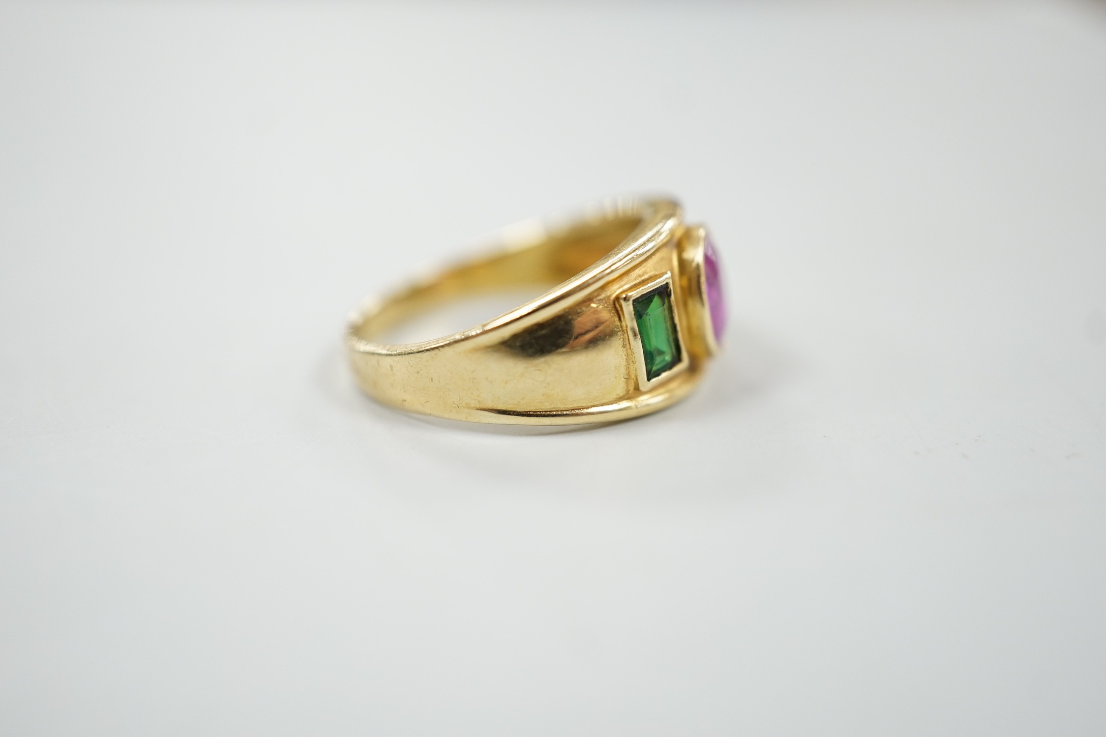 A modern 14k, collet set ruby and green paste? three stone ring, size L, gross weight 4 grams.